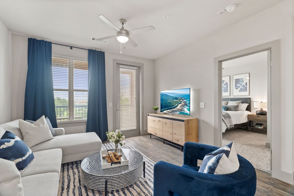 A living room with a white couch, a blue chair, and a television.