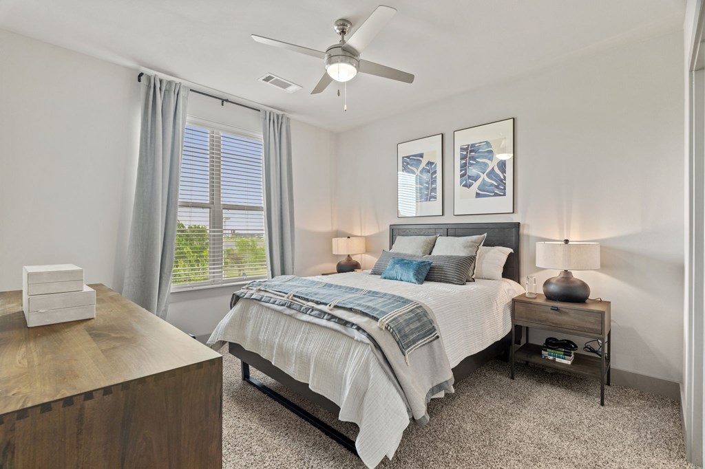 A bedroom with a bed, nightstand, and a ceiling fan.