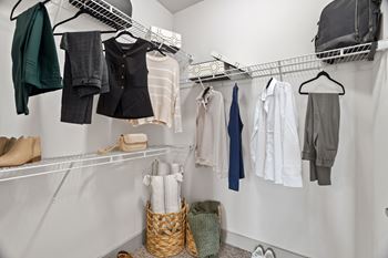 A white closet with clothes and shoes hanging on shelves.
