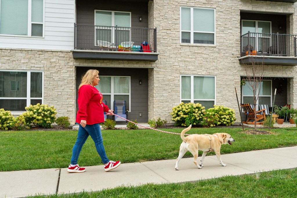a woman walking her dog on a leash in front of a house