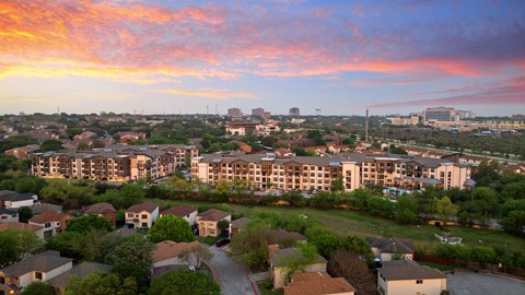 A sunset view of a residential area with apartment buildings and houses.