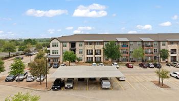 A large apartment complex with a parking lot in front.