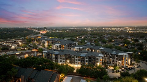 A large hotel complex is lit up at dusk with a view of the surrounding cityscape.