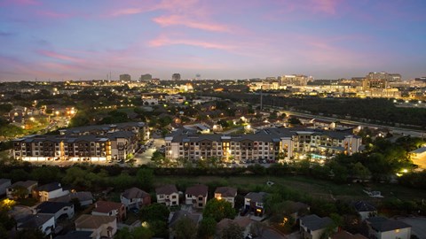 A cityscape at dusk with buildings and houses illuminated.