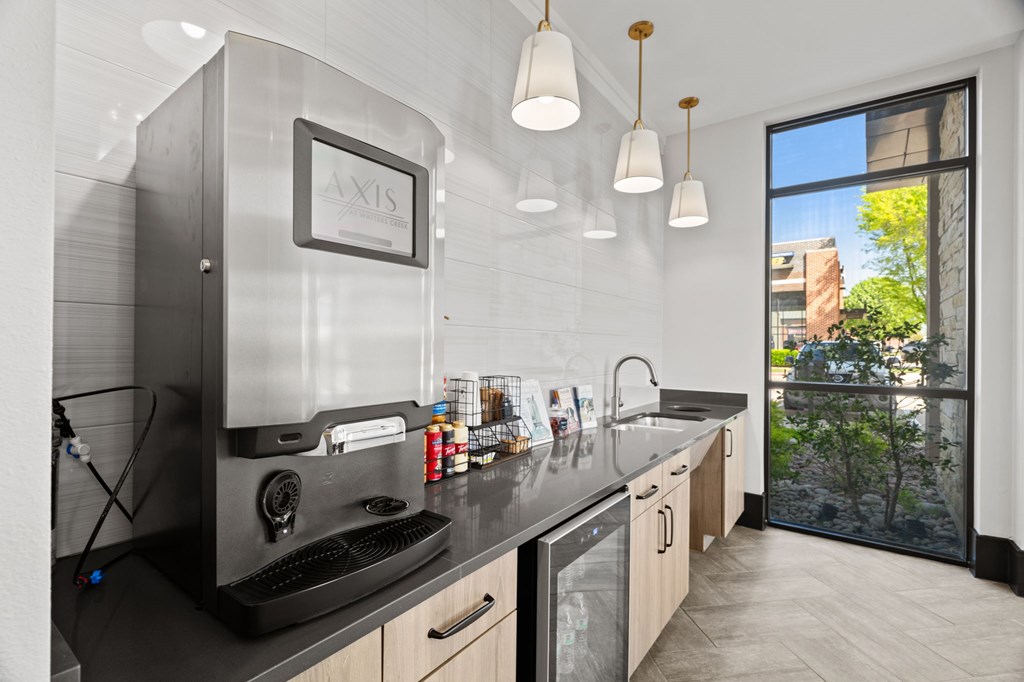 A modern kitchen with a large window overlooking a tree.