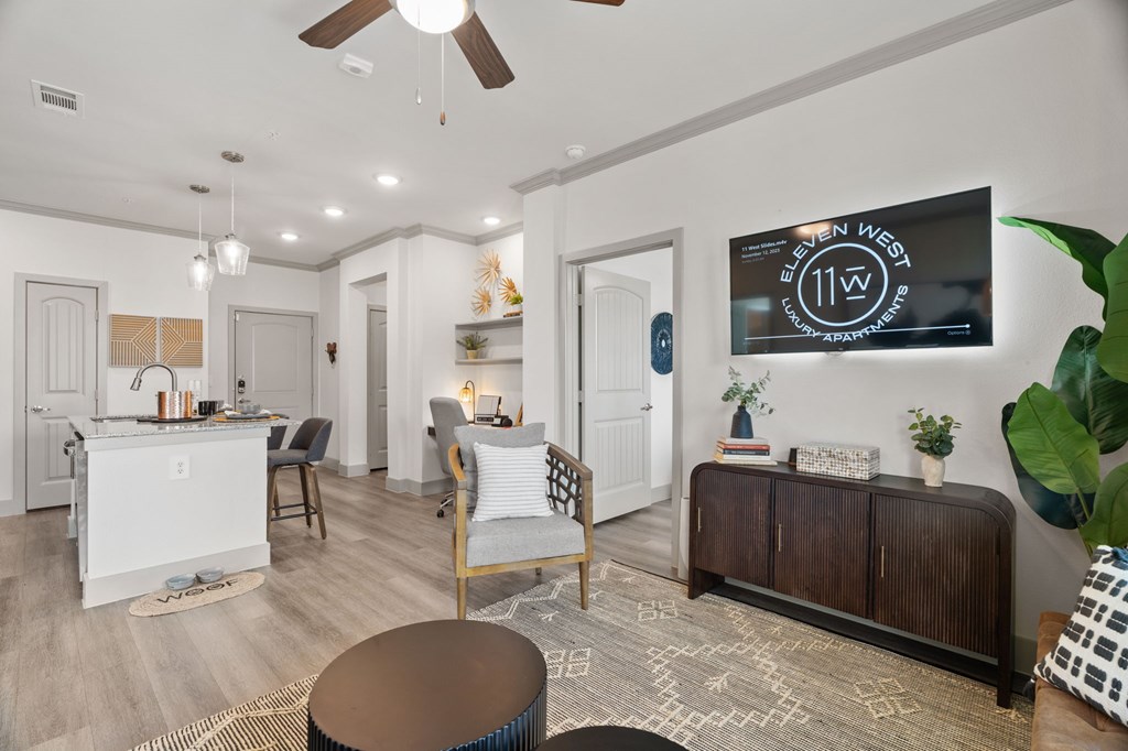 A living room with a white ceiling fan and a television on the wall.