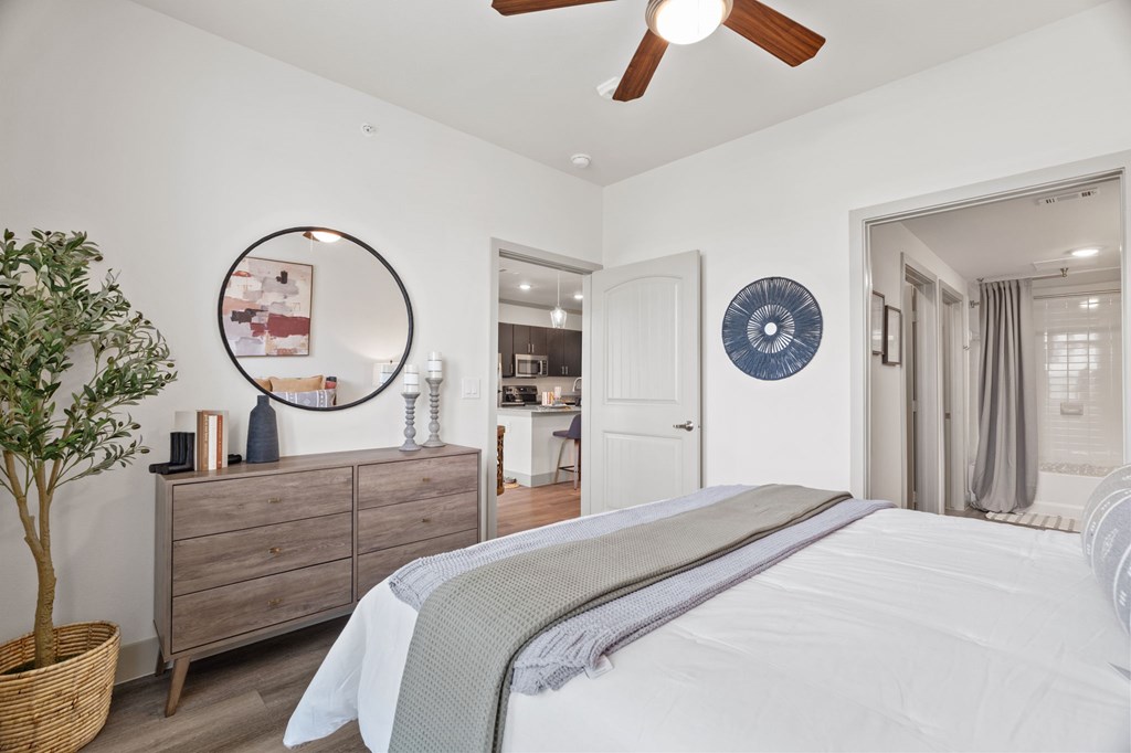 A bedroom with a large bed, a dresser, and a ceiling fan.
