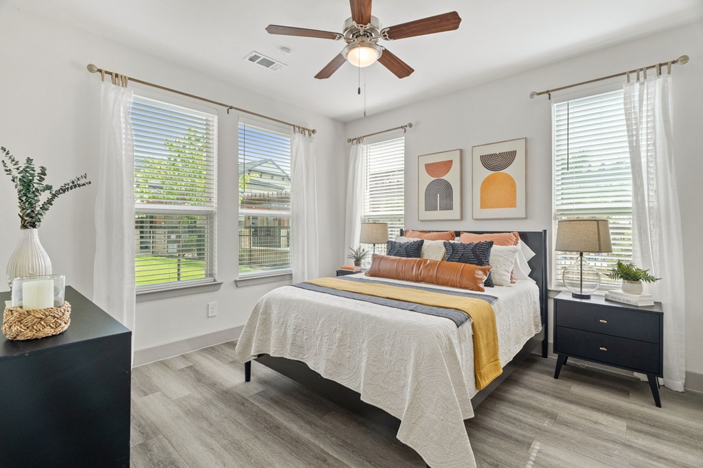 A bedroom with a bed, nightstand, and a ceiling fan.