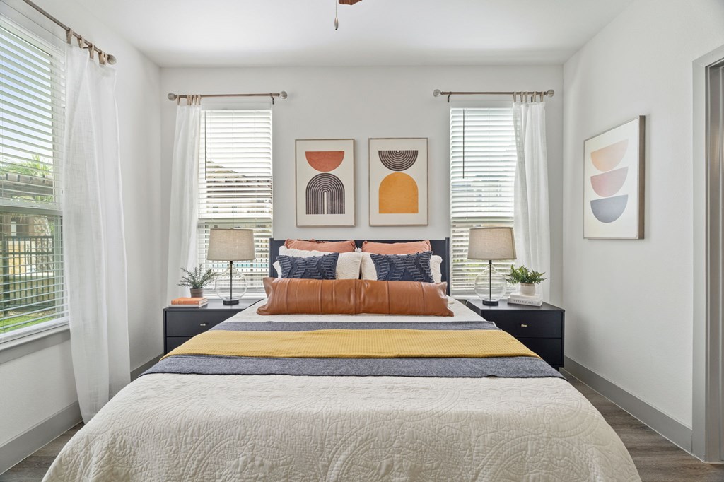 A bedroom with a bed, two lamps, and two framed pictures on the wall.