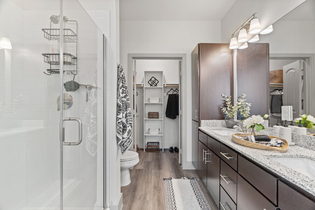 A bathroom with a walk-in shower and a vanity with a marble countertop.