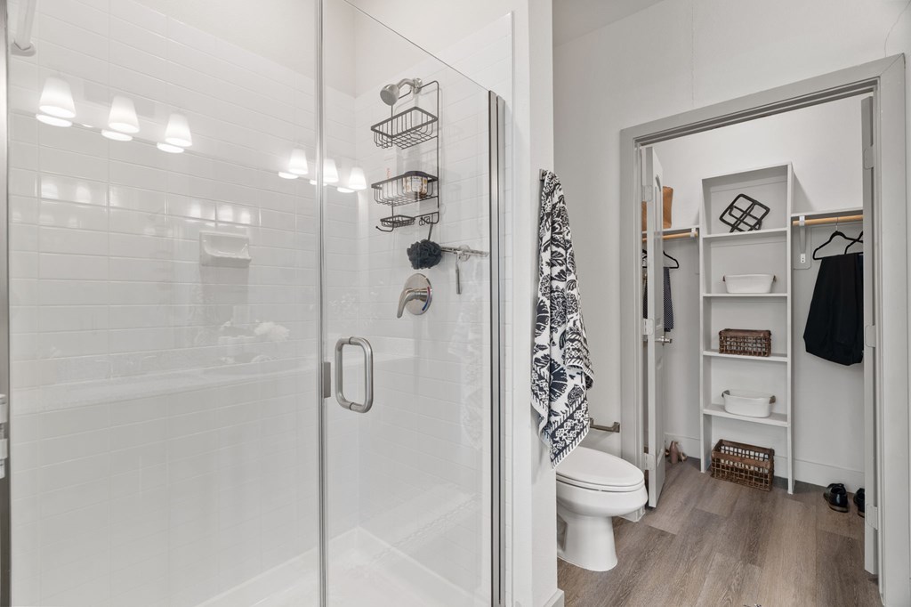 A white bathroom with a walk in shower and a toilet.