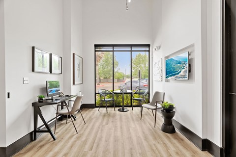 A room with a desk, chairs, and pictures on the wall.