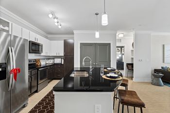 A modern kitchen with a black countertop and stainless steel appliances.