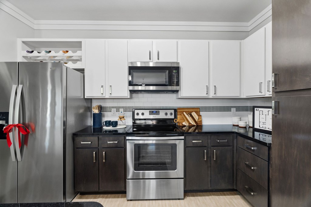 A modern kitchen with a stainless steel refrigerator and black cabinets.