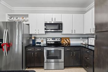 A modern kitchen with a stainless steel refrigerator and black cabinets.