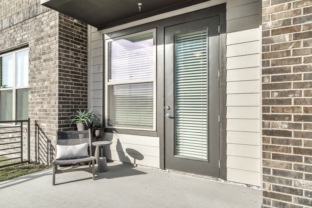 the front porch of a home with a chair and a window