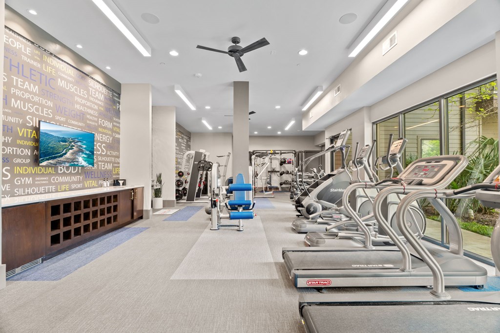 A gym with treadmills and a wall of motivational words.