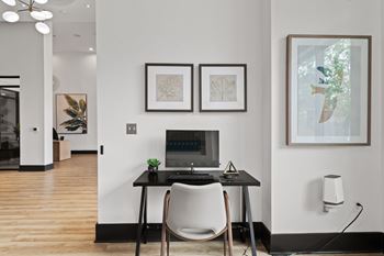 A modern home office with a laptop, chair, and artwork on the wall.