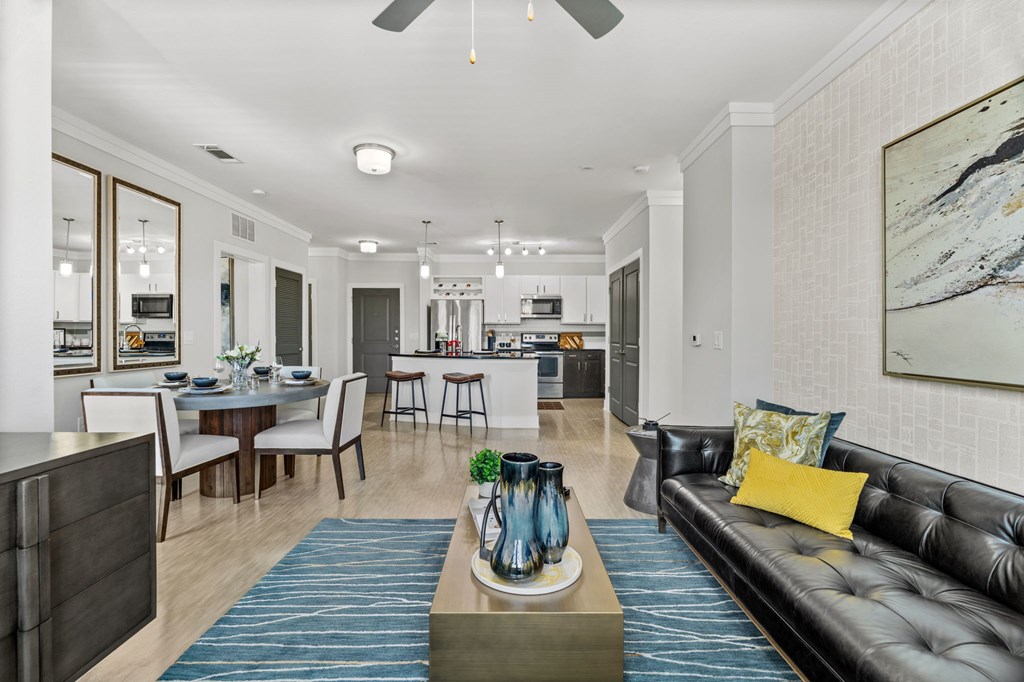 A modern living room with a black leather couch and a dining table set up.