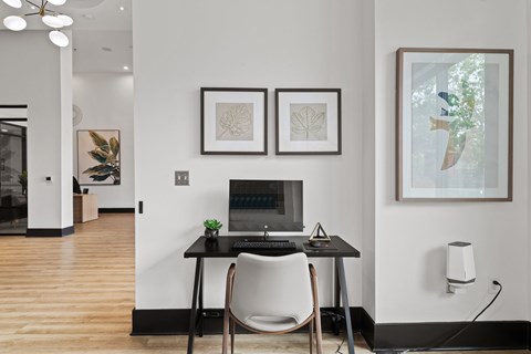 A modern home office with a laptop, chair, and artwork on the wall.