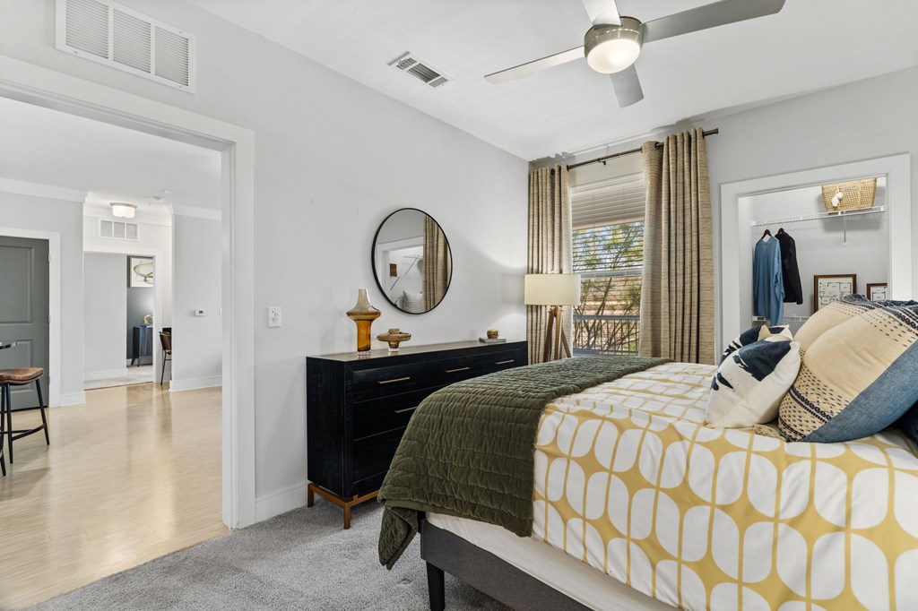 A bedroom with a bed, dresser, mirror, and a ceiling fan.