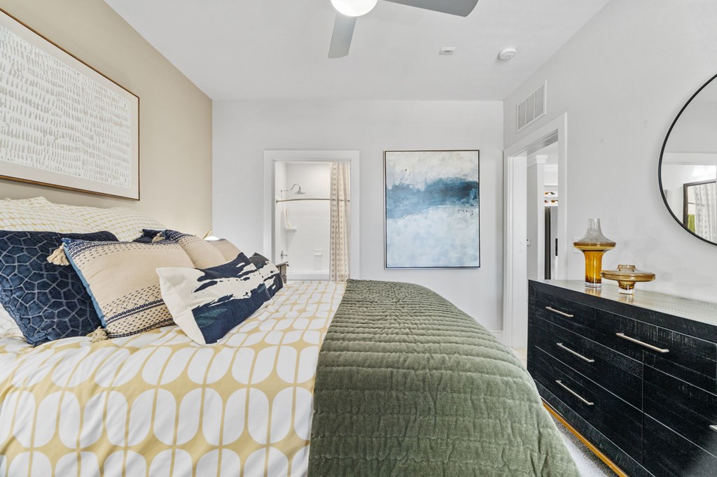 A bedroom with a bed, dresser, and mirror.