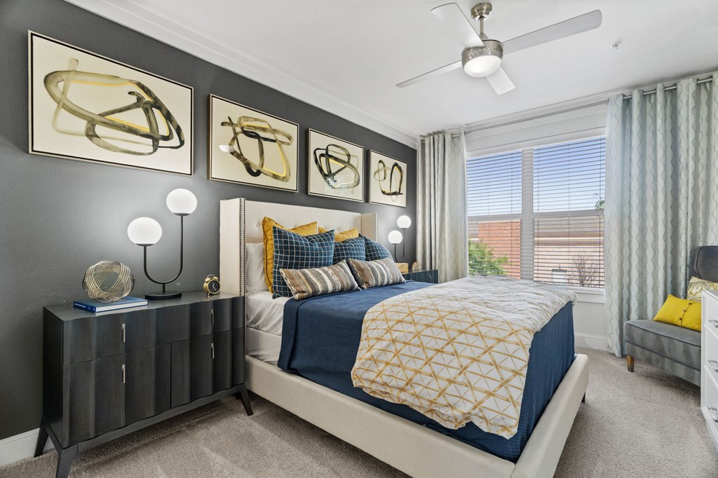 A bedroom with a bed, nightstand, and artwork on the wall.