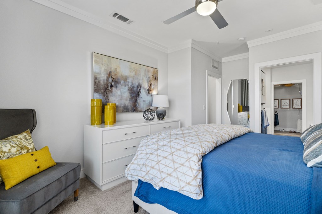A bedroom with a blue bedspread and a grey headboard.