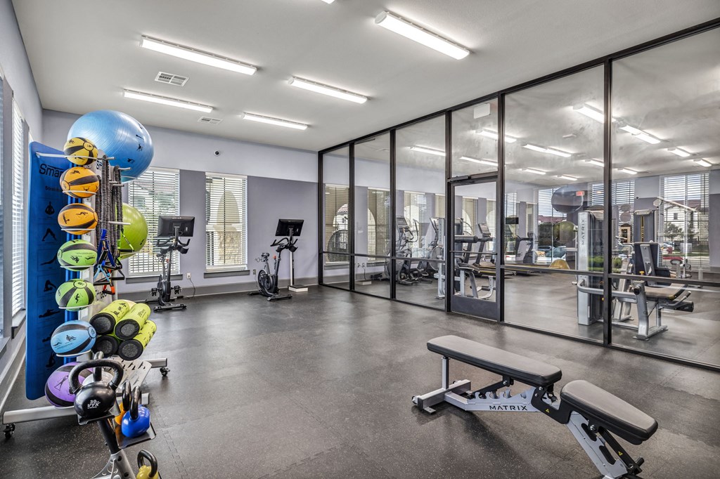 a gym with weights and other equipment and glass walls