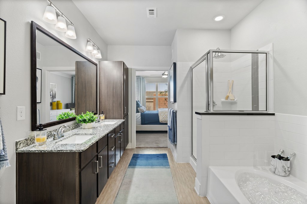 A modern bathroom with a large mirror, a sink, and a bathtub.