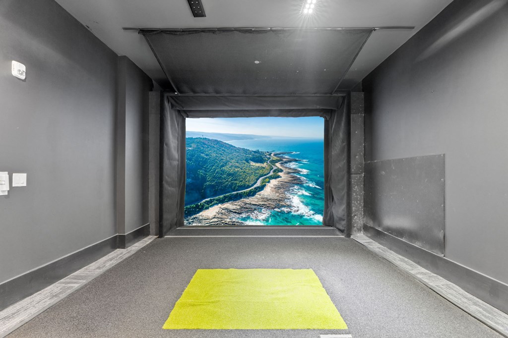 A bright yellow mat is on the floor of a room with a large picture of a coastline on the wall.
