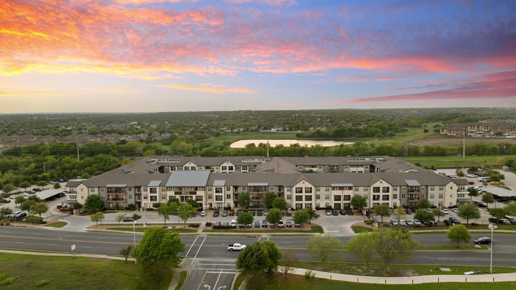 A large apartment complex with a parking lot in front.