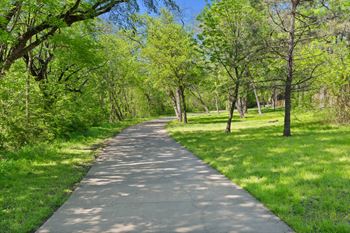 A concrete walkway leads through a green park.