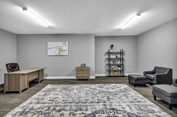 a room with a desk chairs and a large rug