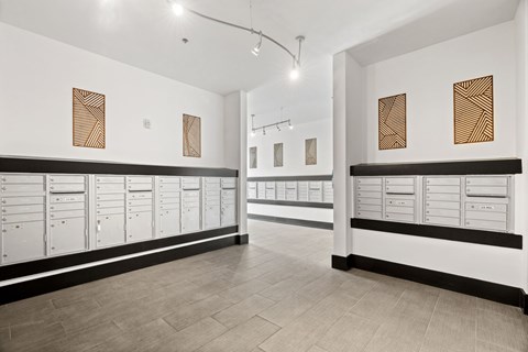 A room with white walls and a black and white floor with a row of drawers on the wall.