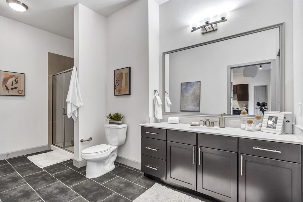 a bathroom with a large mirror and a toilet next to a shower with a glass door