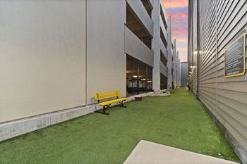 A yellow bench sits in front of a building with a green lawn.