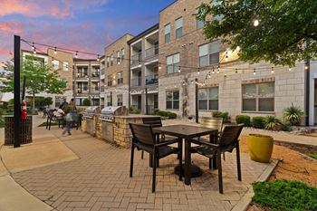 A patio with a table and chairs is surrounded by a brick building.