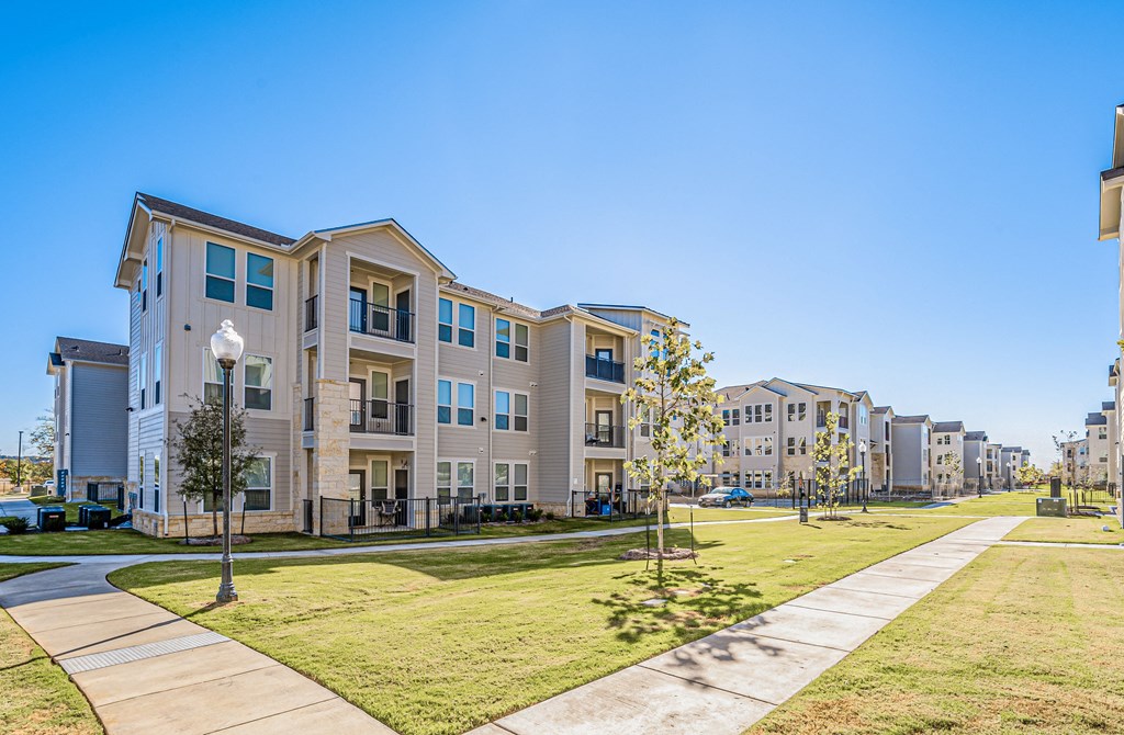 a grassy area with trees and buildings in the background