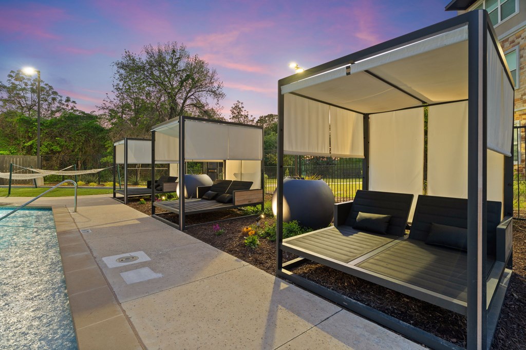 A poolside lounge area with a sunshade and a water feature.