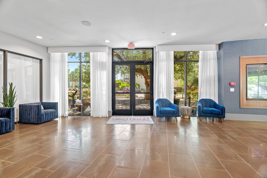 A spacious lobby with blue chairs and a large glass door.