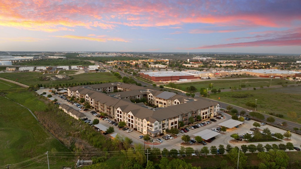 A large apartment complex with a parking lot in front.