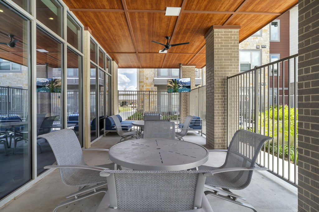 a patio with a table and chairs and a ceiling fan