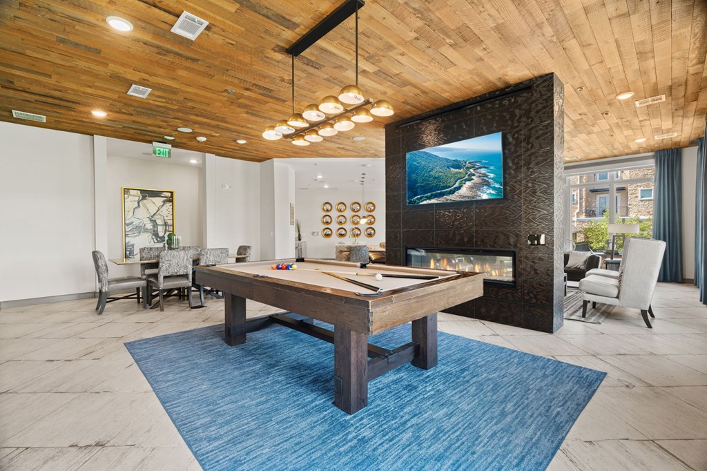 A room with a blue rug and a wooden table.
