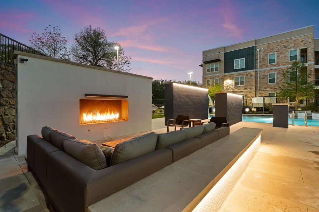 A modern outdoor seating area with a fireplace is set up on a patio.