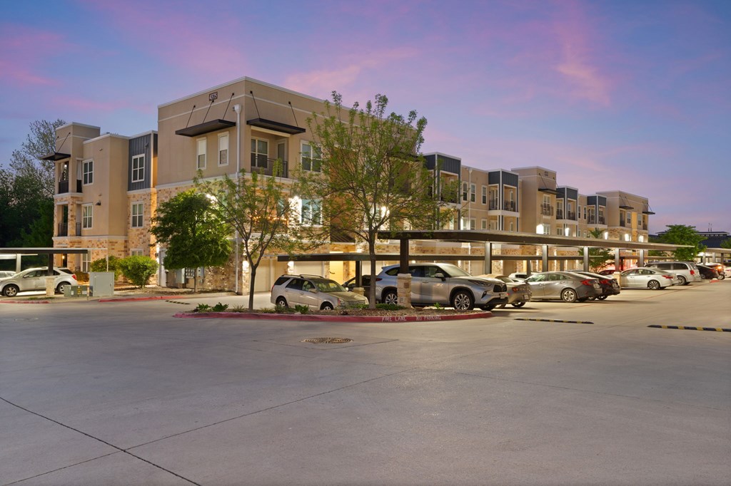 A parking lot in front of a building with cars parked.