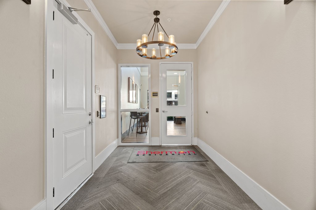A hallway with a rug on the floor and a chandelier hanging from the ceiling.