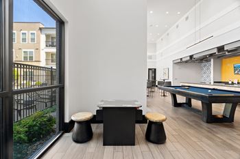A black pool table in a room with a view of a building outside.