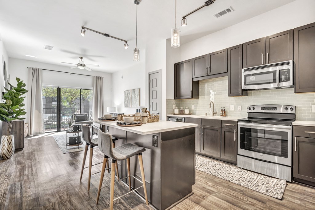 a kitchen with an island and stools in front of a sliding glass door