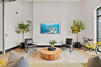 A living room with a painting of a beach scene on the wall.